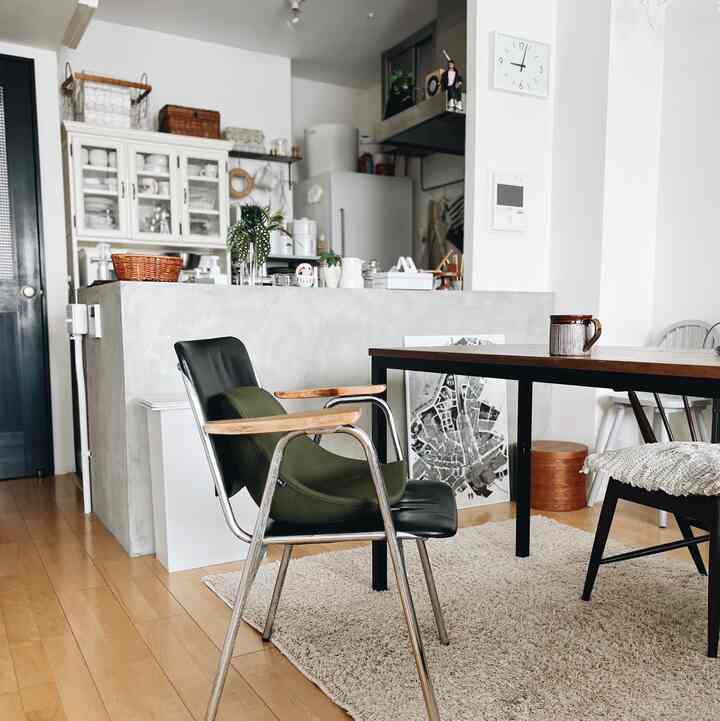 ナチュラルカラーとホワイトのトーンのダイニング、黒いダイニングチェアと木製のダイニングテーブルが配されたモダンで落ち着いた空間