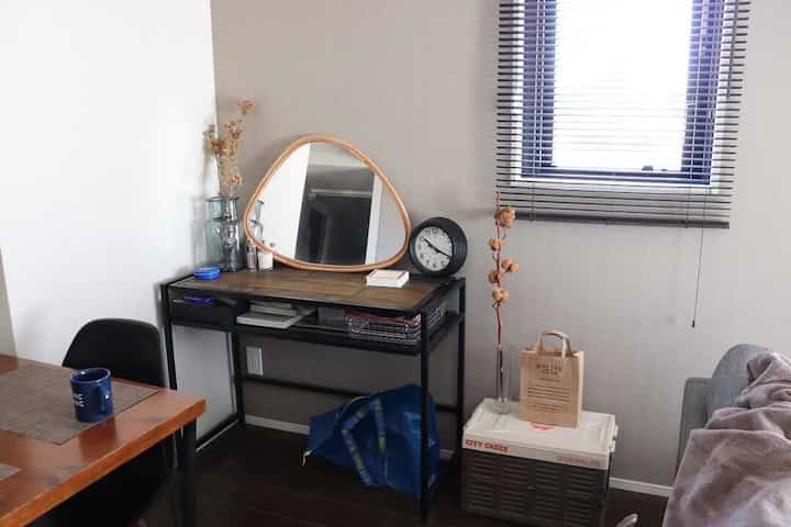 A natural-toned living room for two-person household featuring white walls, gray sofa, brown dining table and IKEA mirror