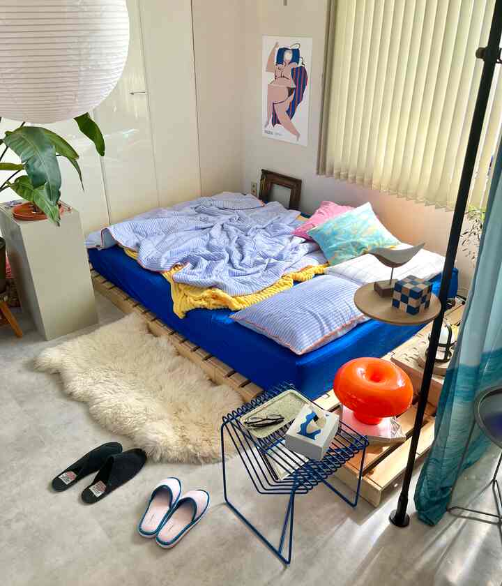 青と白の色調のワンルーム寝室、ベッドと掛け布団が配置された雰囲気のある小さな空間