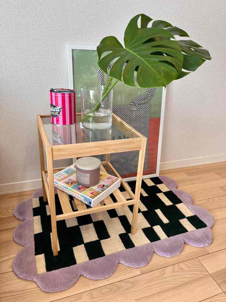 ナチュラルな色調の空間、大きなモンステラの葉と額縁が配置された竹製のナイトテーブルのある雰囲気のあるインテリア