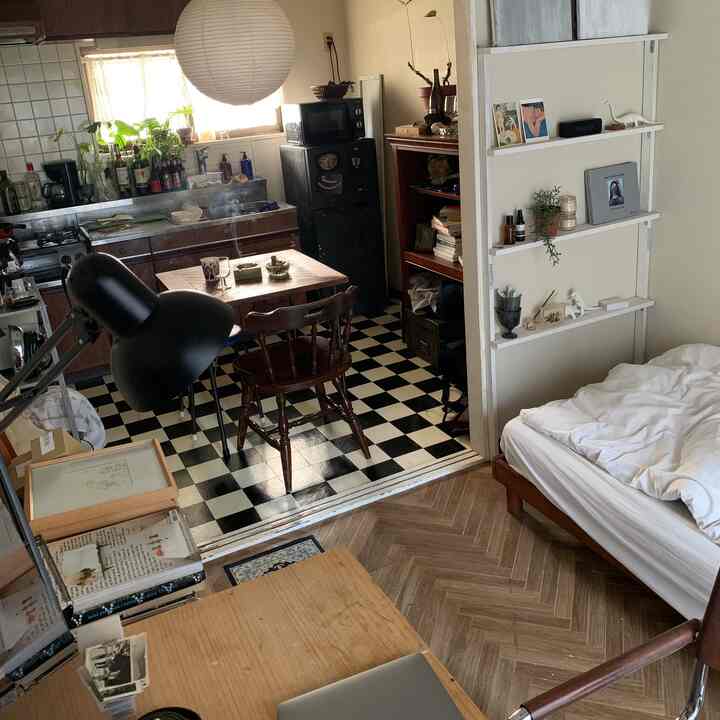 Small apartment living-bedroom with white walls and wood-toned furniture featuring retro accents and modern feeling