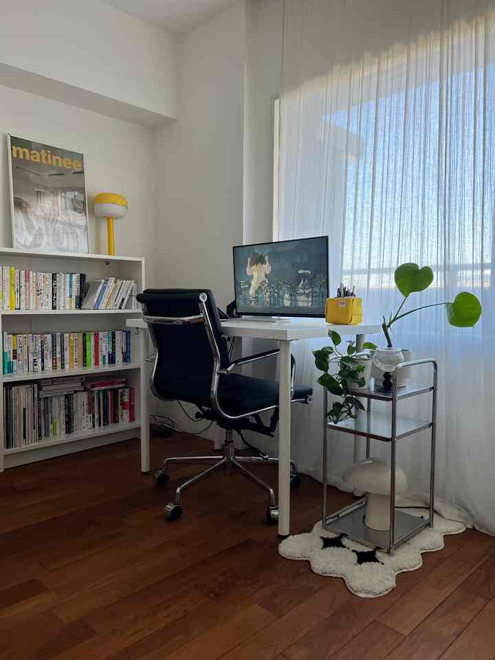 Monotone workspace in white and black featuring desk, office chair, and bookshelf with a clean, bright atmosphere
