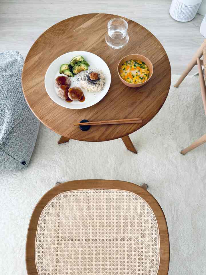 Simple home cafe space featuring a natural wood tone round dining table and rattan dining chair