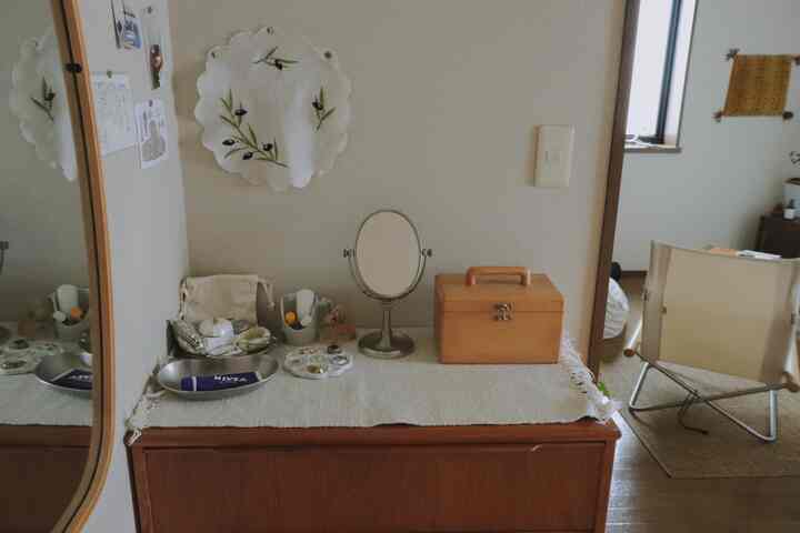 White and brown toned bedroom featuring a dresser with round mirror and natural light creating a cozy atmosphere