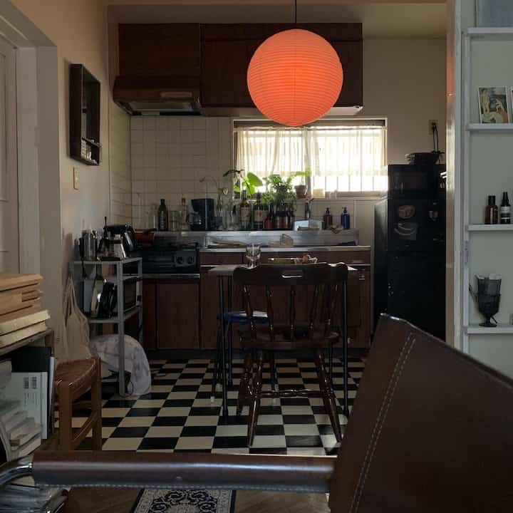 ブラウン調の狭いアパルトマンのキッチン・ダイニングスペース、オレンジ色のペンダントライトが印象的なナチュラルなインテリア