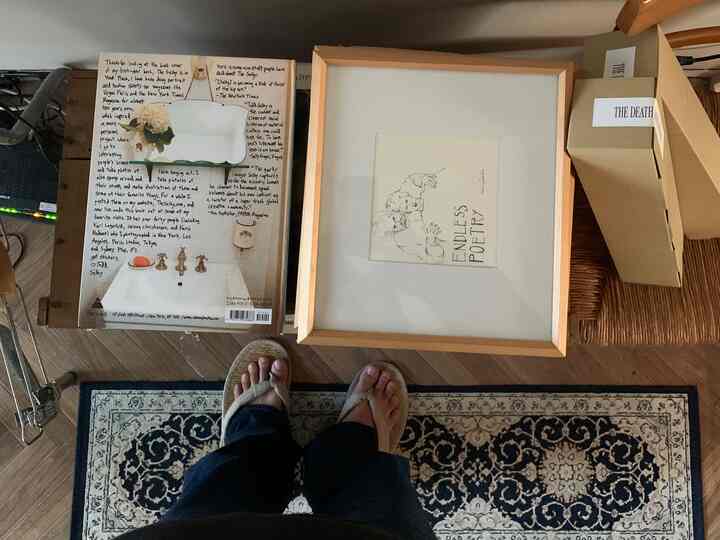 木目調の床とラグ、デスクの上に額縁と本が置かれた落ち着いた空間