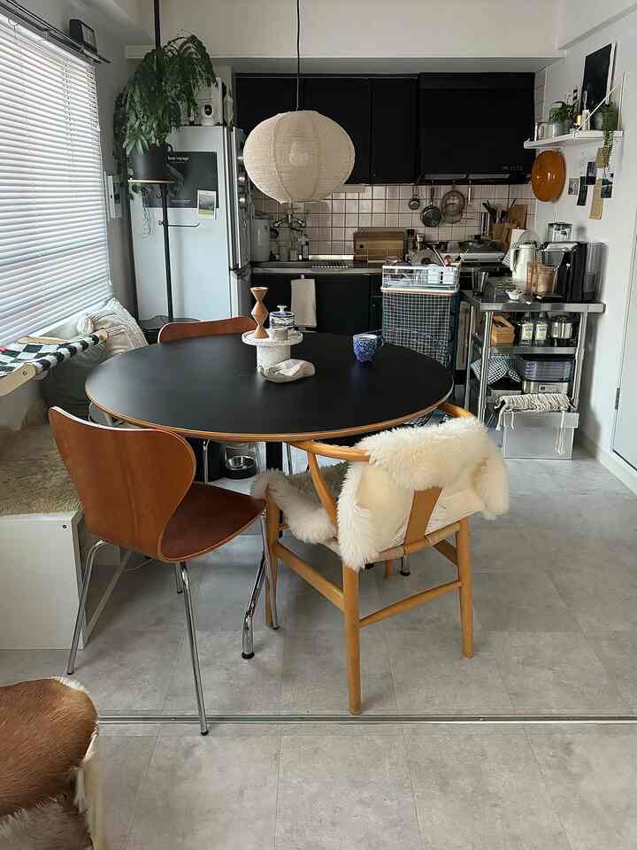 木目調と黒を基調とした一人暮らし用ダイニングルーム、丸テーブルと椅子が配置されたシンプルで落ち着いた空間