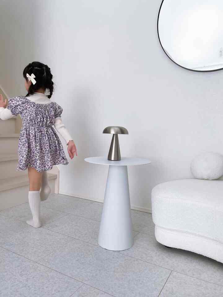 White and natural tone living room featuring round mirror, side table, and a child creating a cozy atmosphere