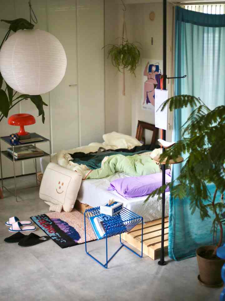 White and blue toned single household bedroom featuring natural plants and minimalist furniture creating a cozy atmosphere