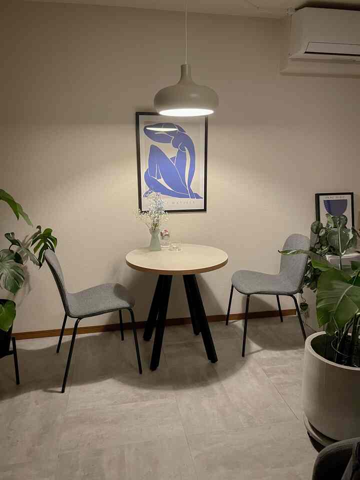 白い壁とグレーのダイニングチェアが並ぶ、カフェ風の2人用ダイニング空間