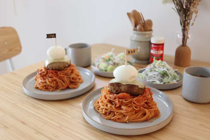 ナチュラルな木目調のダイニングテーブルに皿とカトラリーが配置された雰囲気のあるダイニングスペース