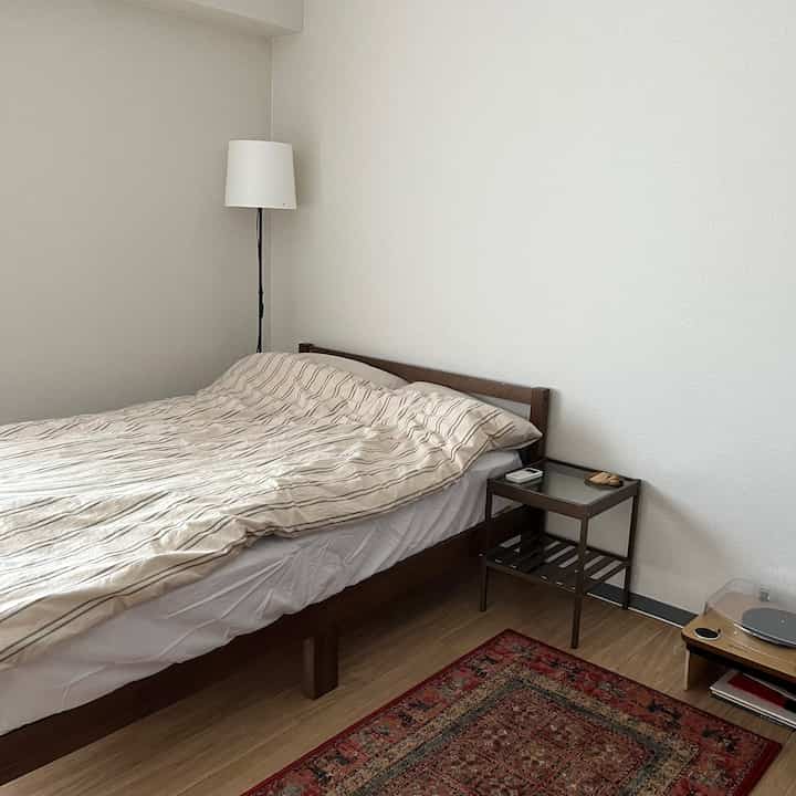 Natural toned bedroom featuring wooden bed and nightstand in a clean and simple space