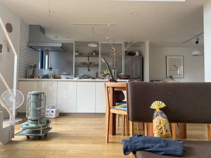 Natural modern living and kitchen space with white and brown tones, featuring a sofa and dining table in a cozy interior