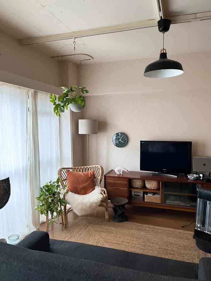 Beige-toned living room featuring natural furniture, a rattan chair, and a black sofa creating a cozy atmosphere