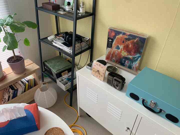 Cozy interior featuring yellow walls, black metal shelving, and a white cabinet with retro accessories