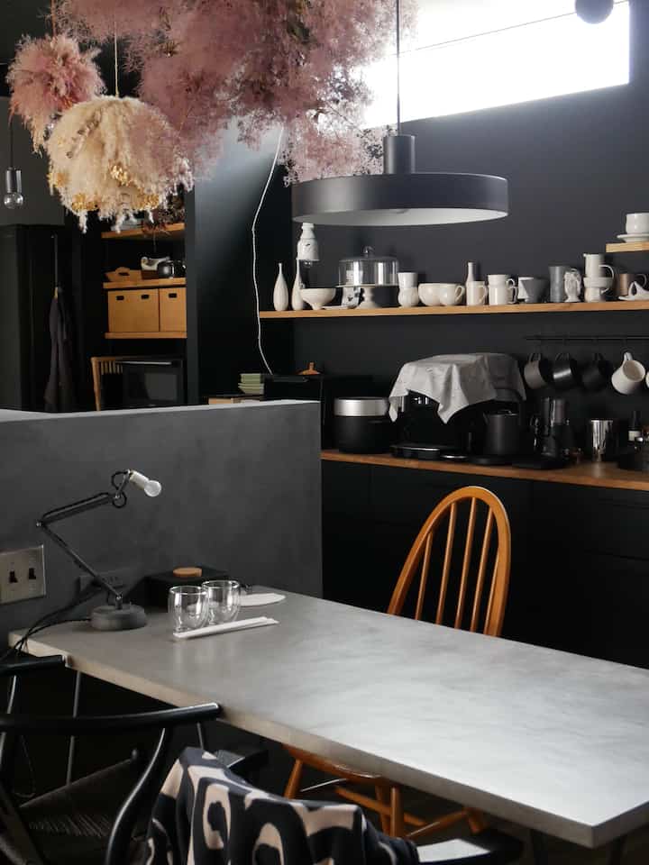 黒とグレーのトーンのモダンなキッチン、モールテックスのテーブルとアーコールチェアが配置された洗練された空間