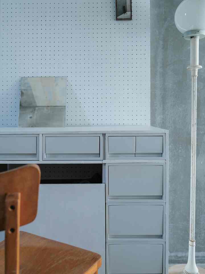 Natural wooden chair and white-gray toned room featuring a clean, modern dresser with pegboard wall