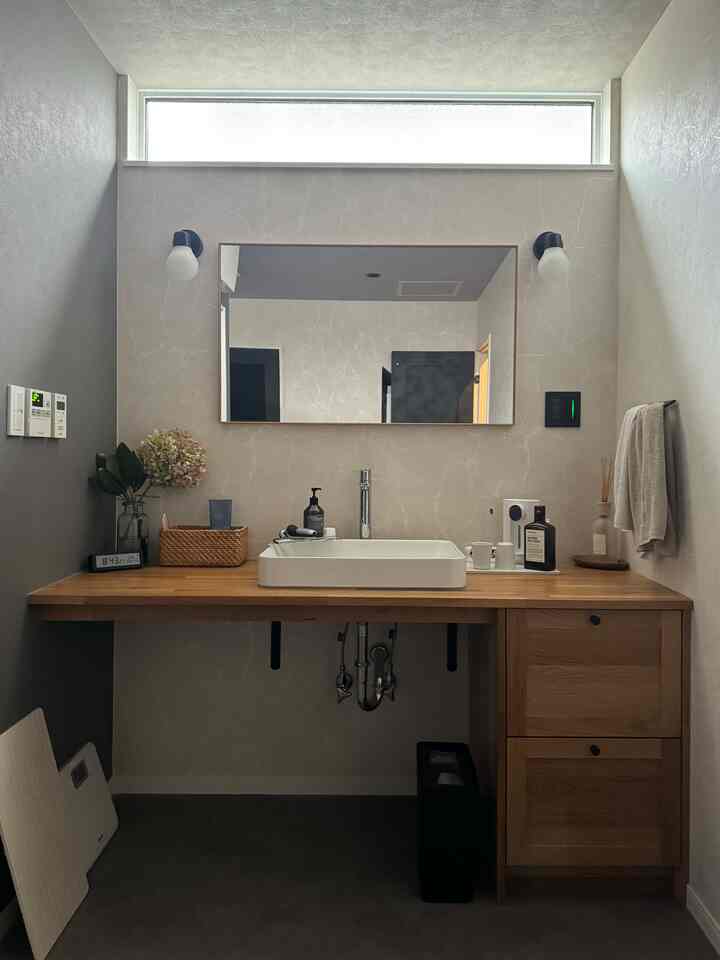 ナチュラルな木目調のパウダールーム、清潔感ある洗面台と収納キャビネットが配置されたシンプルな空間