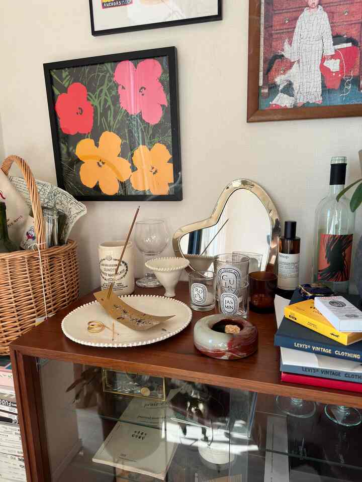 ベージュの壁と茶色の木製キャビネットにキャンドルやお香立て、ハート型の鏡が配置された落ち着いた香りコーナー