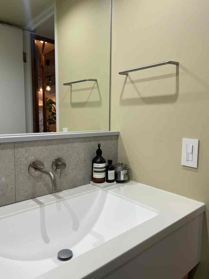 ベージュの壁と白い洗面台が配置されたモダンなバスルームのインテリア