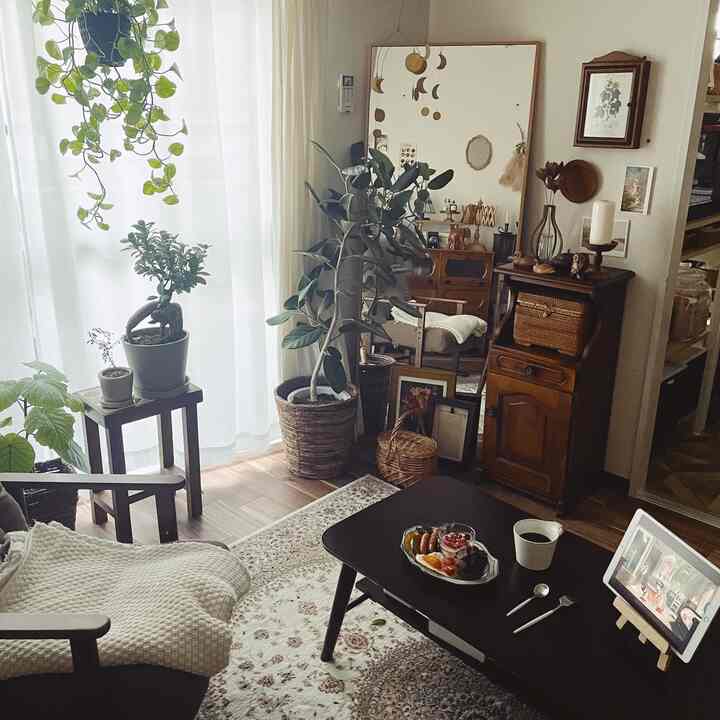 Natural-toned living room featuring large mirror, wood furniture, dining table, and plants creating a cozy atmosphere