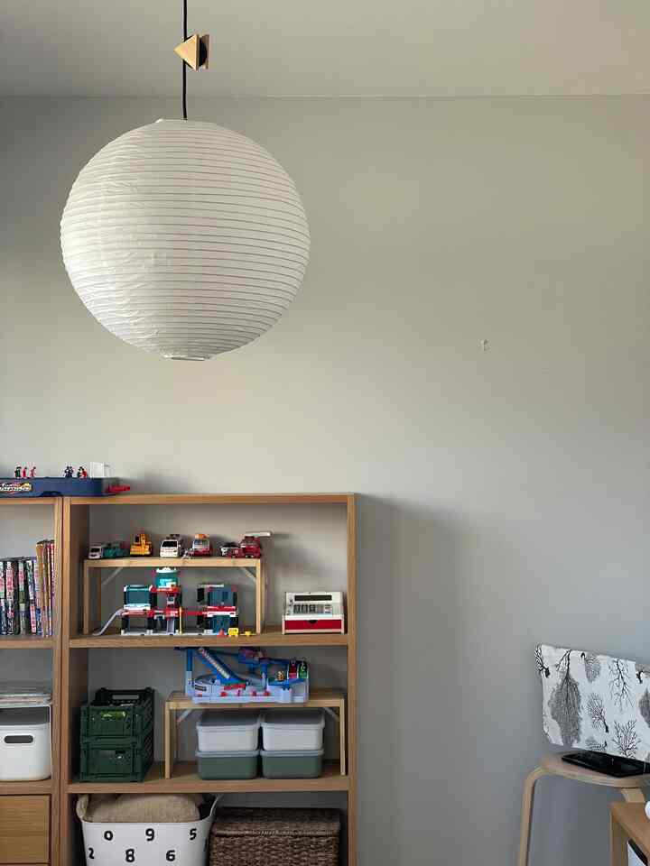 白い壁と木目調の棚、子供用おもちゃと収納箱が配置されたナチュラルな雰囲気の子供部屋