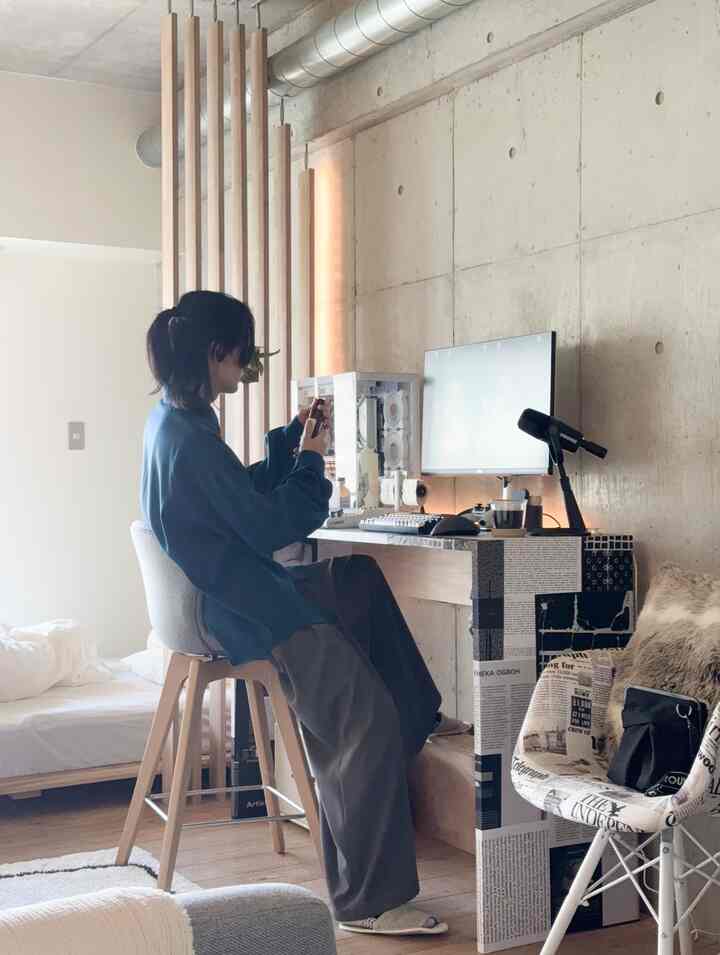 Natural toned modern studio apartment featuring a desk with computer, bedroom area, creating a cozy home office space