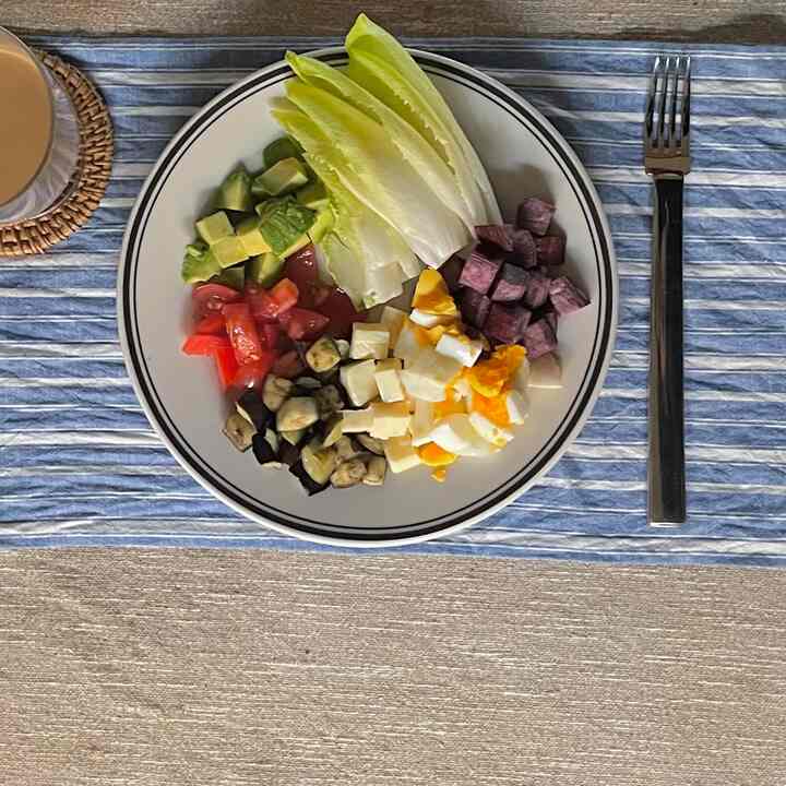 ブルーストライプのテーブルマットに白い皿が置かれ、野菜とゆで卵が盛り付けられた印象的なキッチンの食事空間