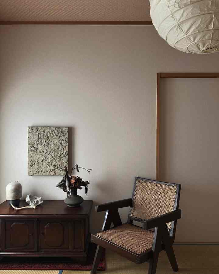 Natural tone living room with beige walls, brown wooden armchair and decorative objets on cabinet