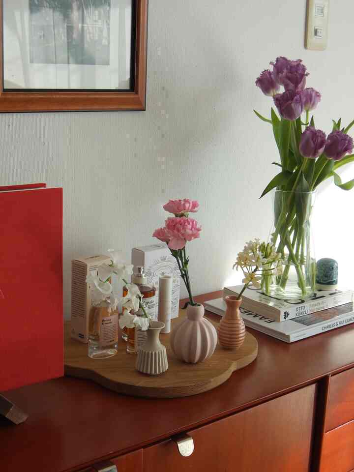 ブラウンとホワイトの北欧リビング、木製サイドボードの上にピンクの花瓶や小物が調和して配置された雰囲気のあるインテリア