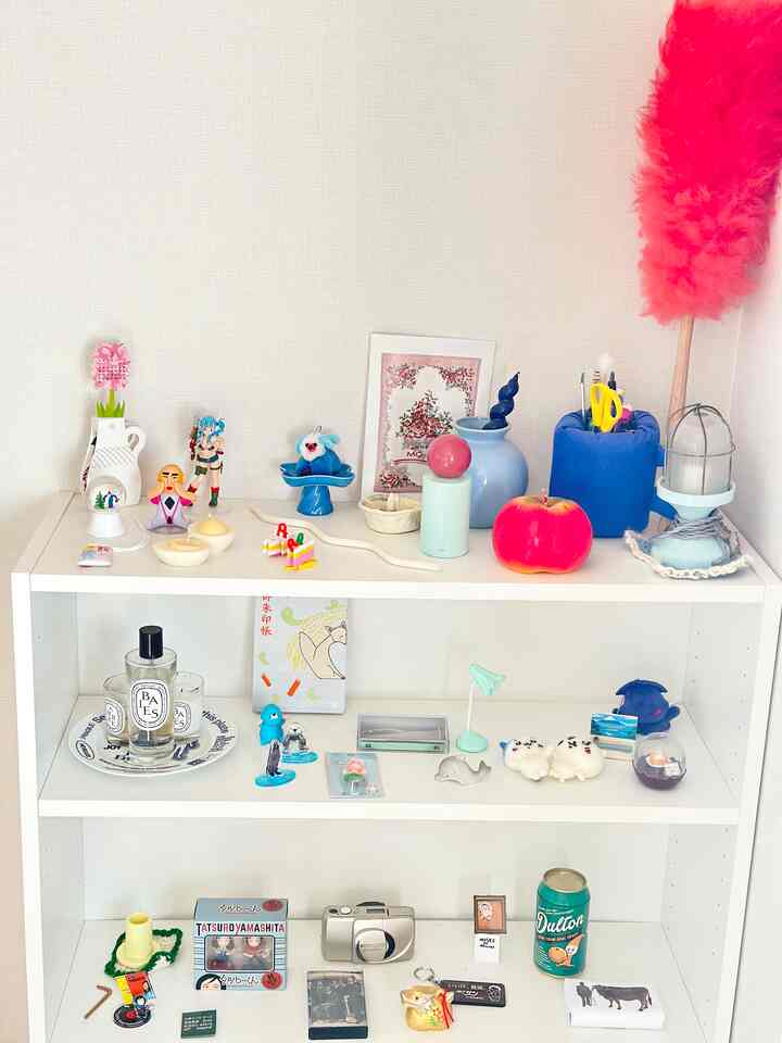 White-toned bookshelf featuring various decorative items and floral art with a simple, open atmosphere