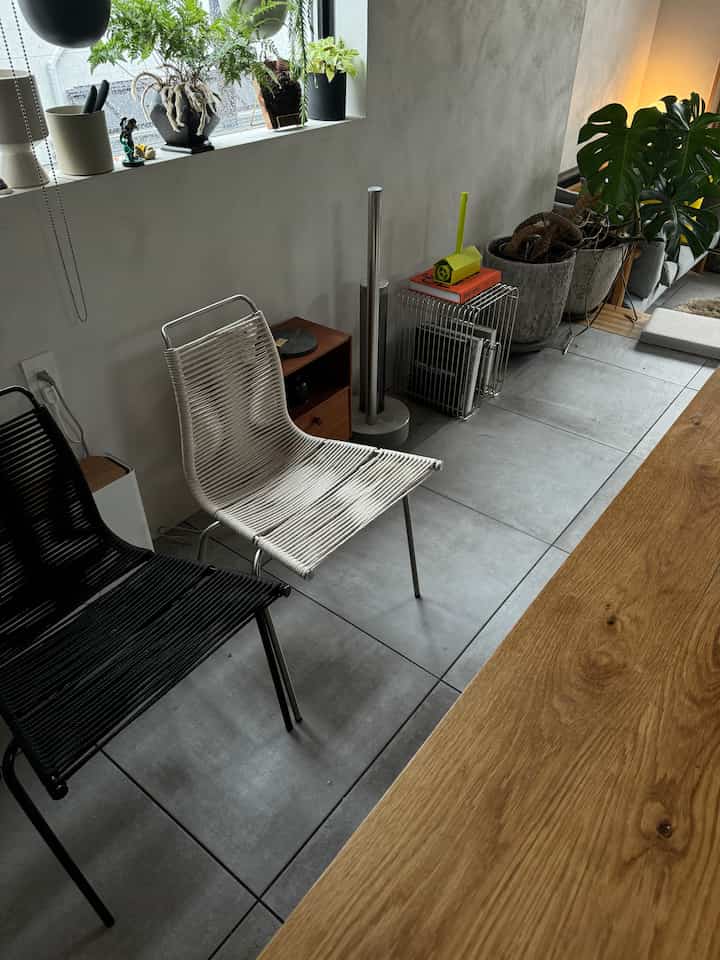 ナチュラルトーンのダイニングルーム、木製のテーブルと黒と白の椅子が配置された清潔感のある空間