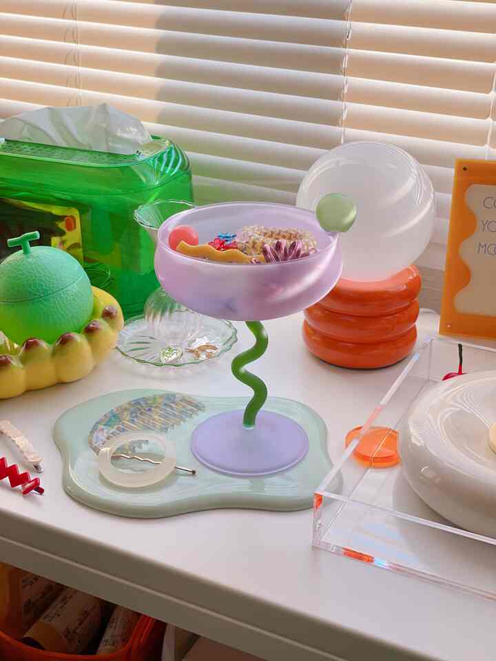 パステルパープルとグリーンのコンビネーションのトレイと曲線脚のオブジェが配置された、温かみのあるレトロなテーブルスペース