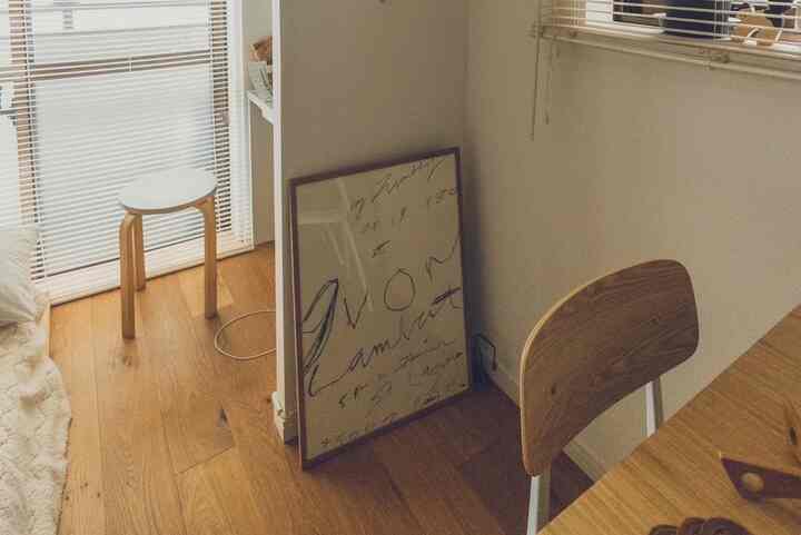 明るい木目調と白を基調としたリビング、スツールとポスターが配置された温かく自然な雰囲気のインテリア