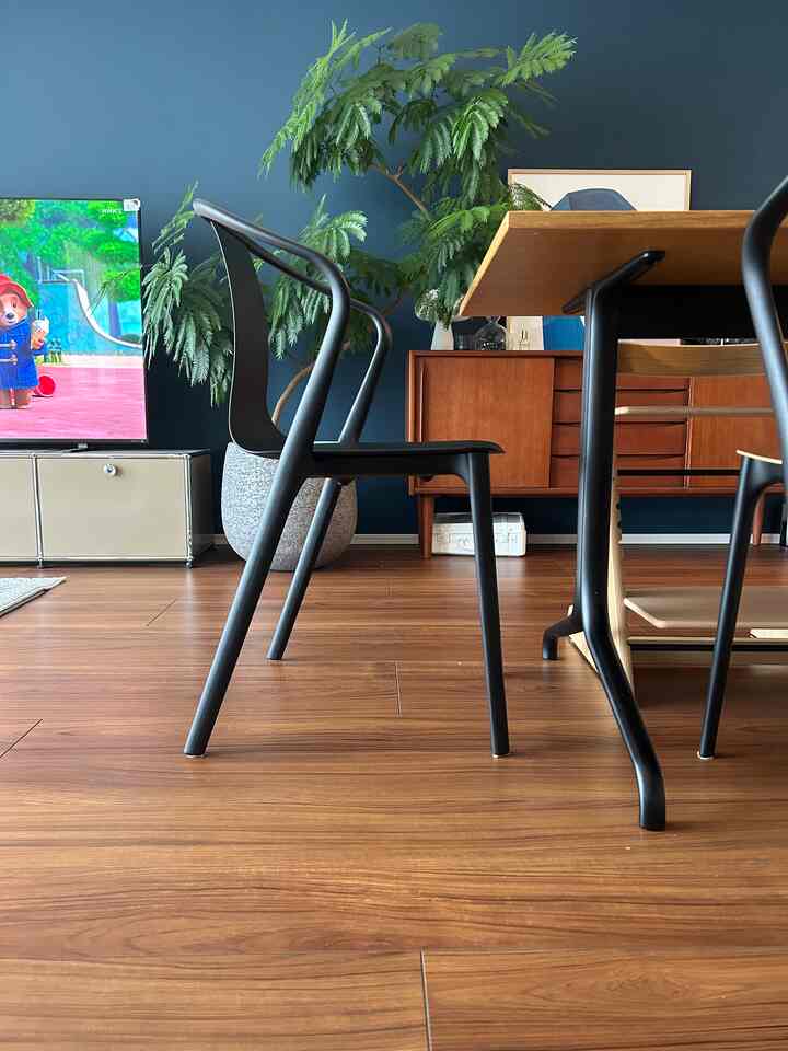 ダークブルーの壁と木目調のダイニングテーブル、黒いアームチェアが調和した印象的なリビング空間