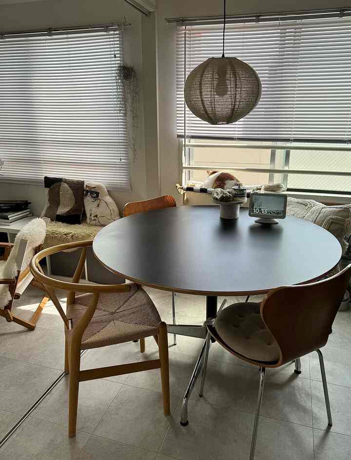 白と木目調のミッドセンチュリーモダンな一人暮らし用ダイニングルームで、窓辺に猫がいる落ち着いた空間