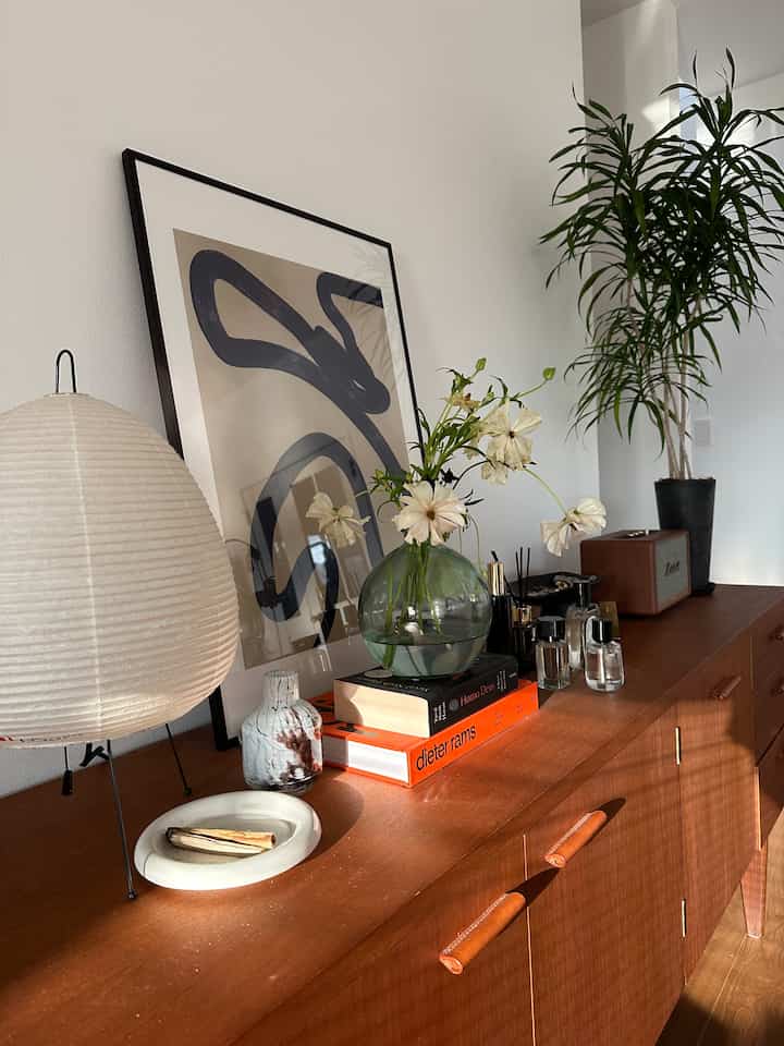 暖かい木調のリビングルームキャビネット、ランプや花瓶、植物が配置された北欧ヴィンテージ風の印象的な空間