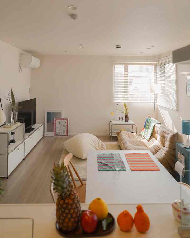 Bright living and dining room in beige and white tones featuring simple furniture arrangement and natural sunlight