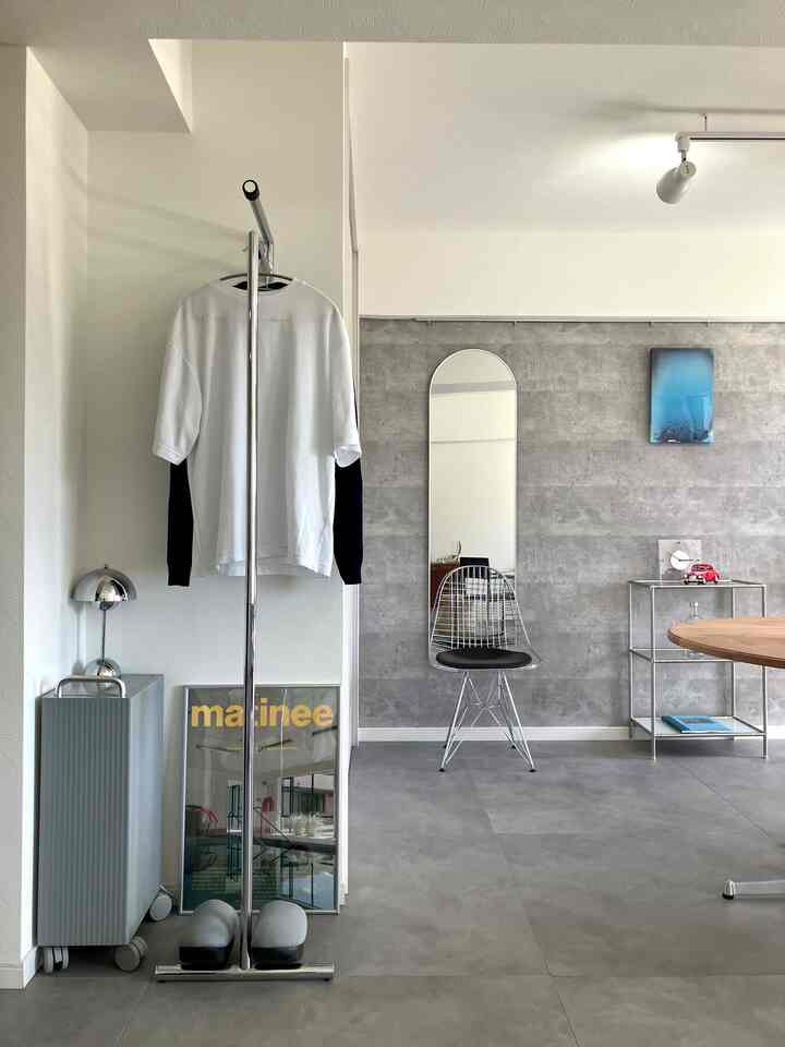 グレーのトーンのモダンダイニングルーム、高い鏡とメタル家具が配置されたさっぱりとした空間