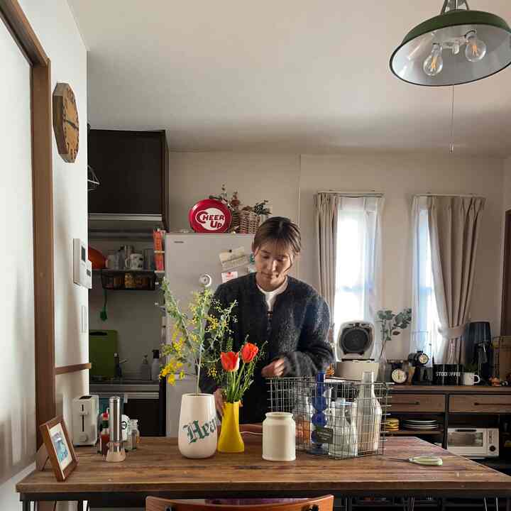 ナチュラルカラーのダイニング、木製ダイニングテーブルと花瓶が配置された温かみのある空間