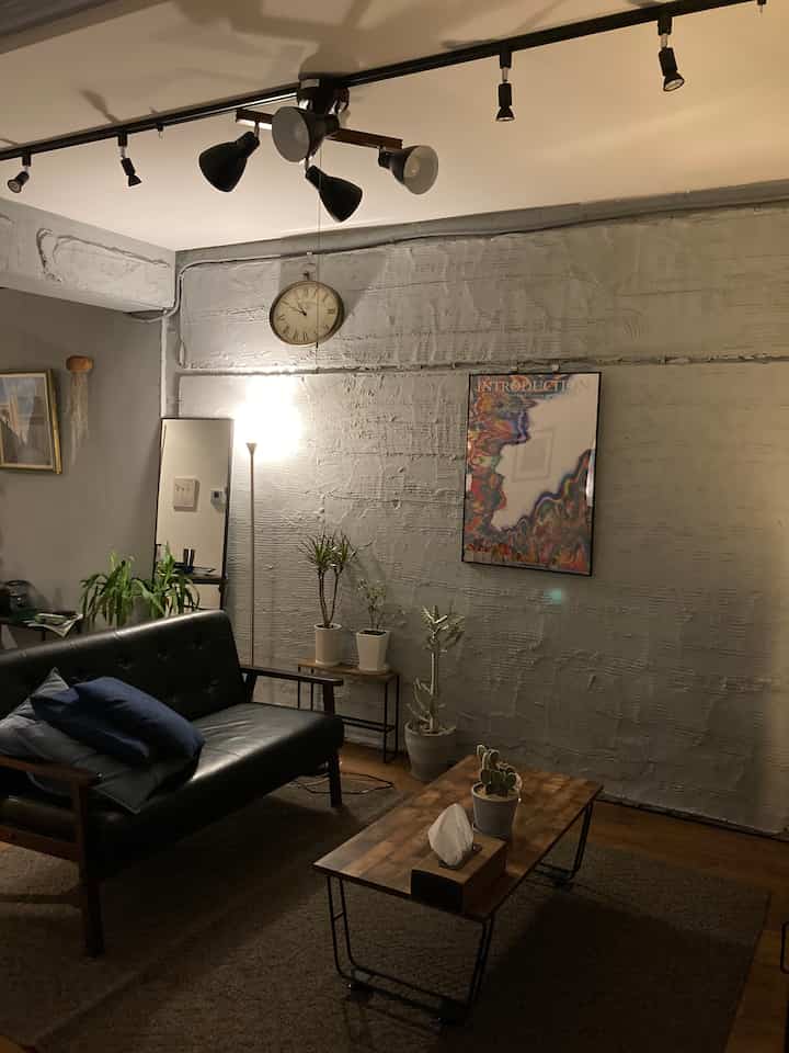 スカイブルーの壁が印象的なリビング、革製のソファと木製コーヒーテーブル、植物やフロアランプが配された雰囲気ある北欧スタイルの空間