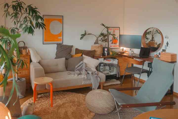 Wood tone and orange-accented two-person living room featuring sofa and desk, creating a cozy atmosphere