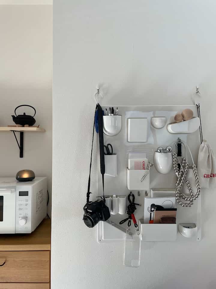 ホワイトとナチュラルウッドトーンのキッチン壁面収納、壁掛け収納と電子レンジが配置された清潔感のある空間