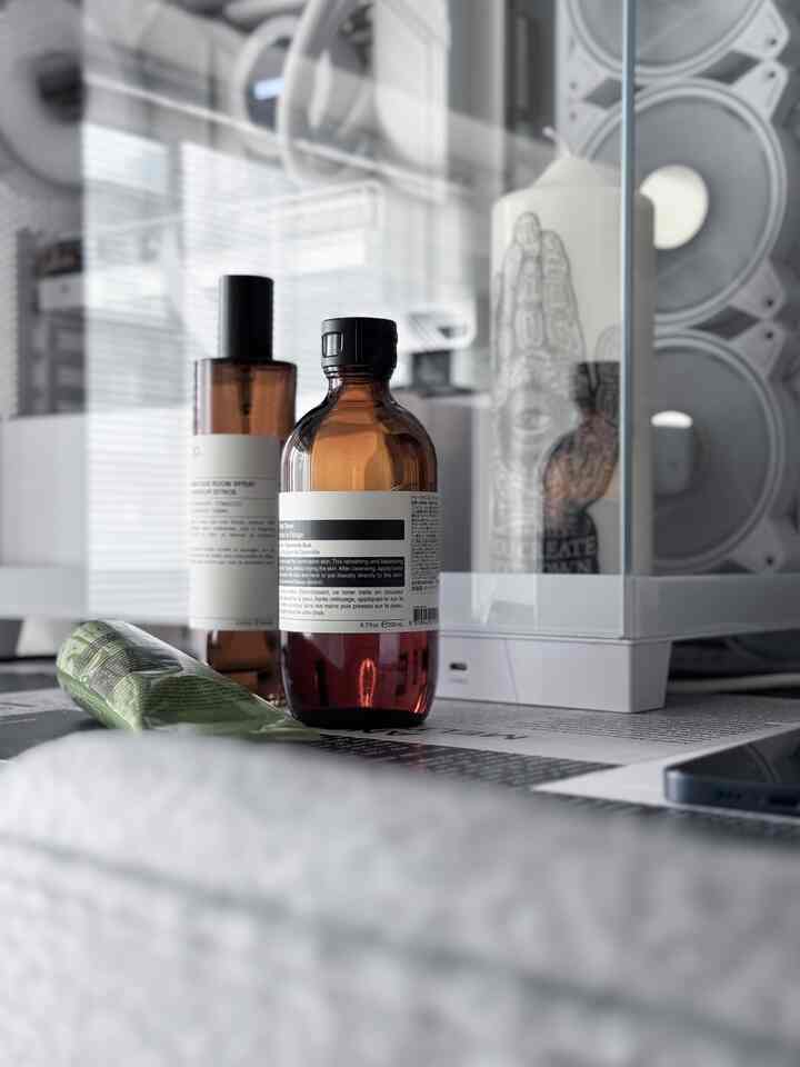 A clean vanity setup featuring white and brown tones with aromatic bottles and a decorative candle in a glass case
