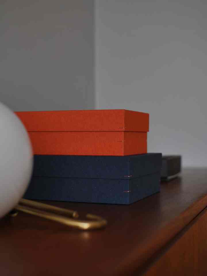 ブラウンの木目調の上にネイビーと赤の箱が置かれたシンプルな雰囲気のインテリアオブジェ