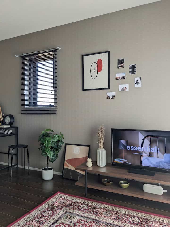 Brown wood tone flooring and black furniture blend in a two-person household living room with plants and rug creating a cozy atmosphere.