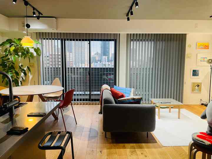 Modern living and dining room in white and wood tones featuring gray sofa and round dining table