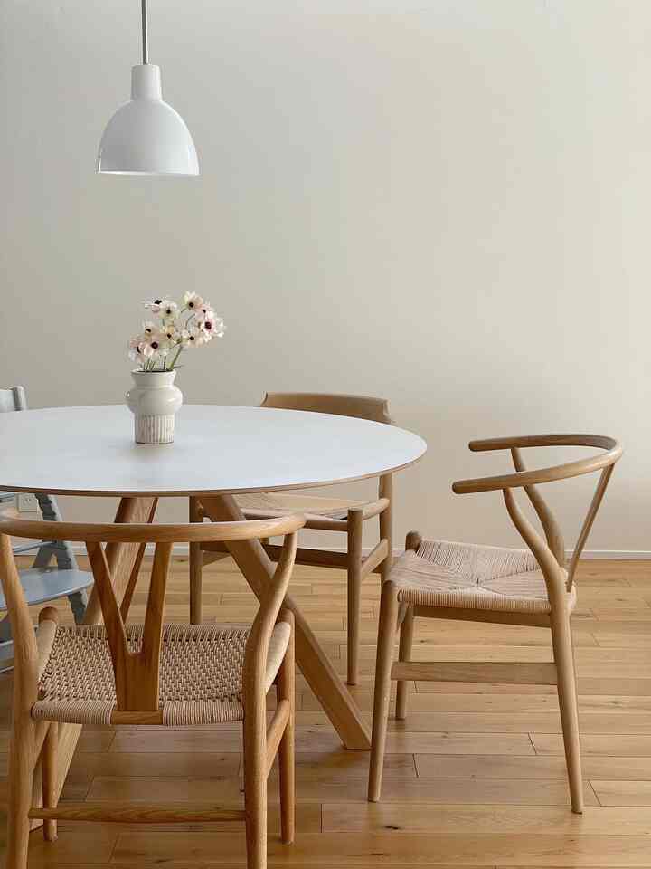 明るい木目調の床とラウンドテーブル、中央に花瓶と花が置かれたナチュラルなダイニングのインテリア