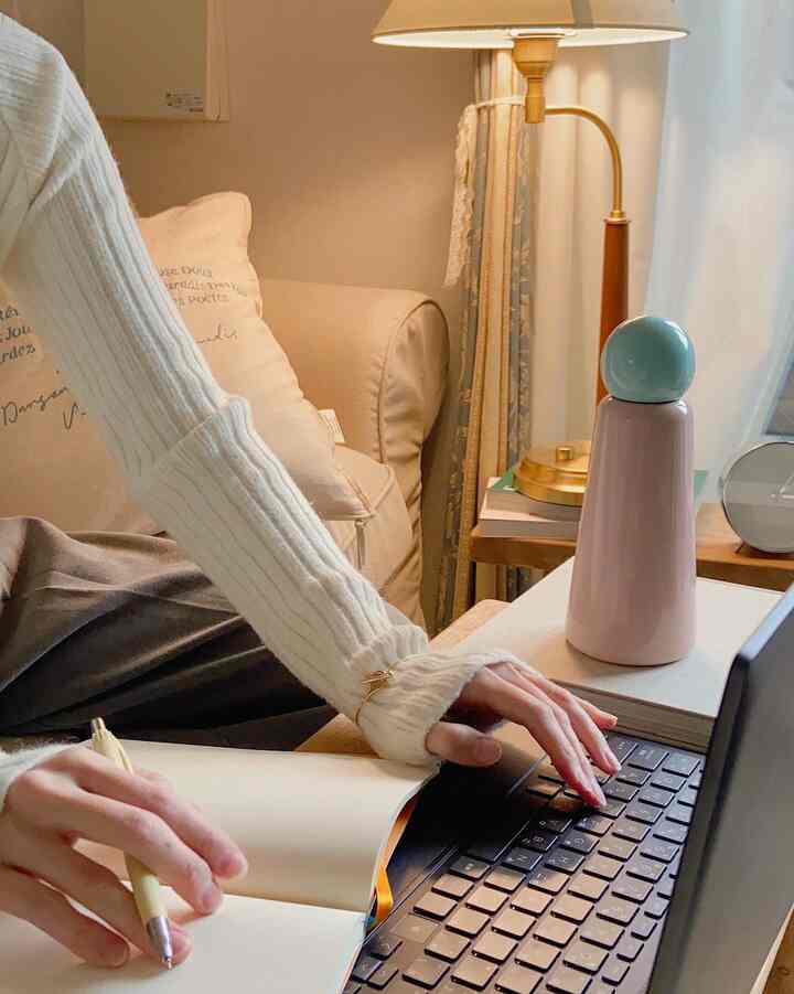 暖かいベージュ調のリビング、ノートパソコンとテーブルランプが置かれた雰囲気のあるホームオフィス