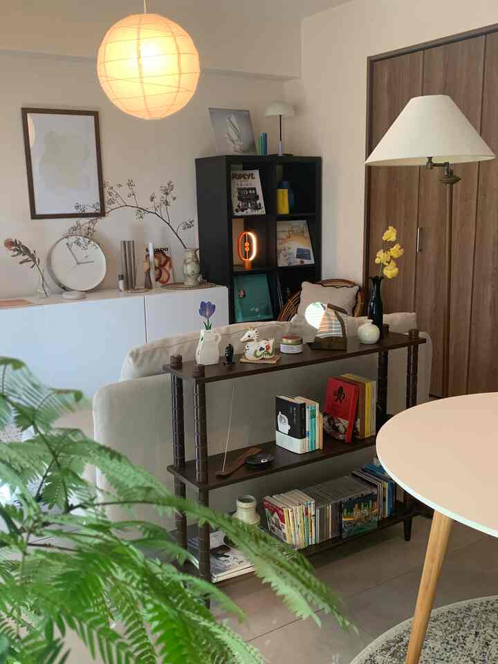 Natural toned living room with beige sofa, wooden shelves, and a white dining table creating a cozy atmosphere